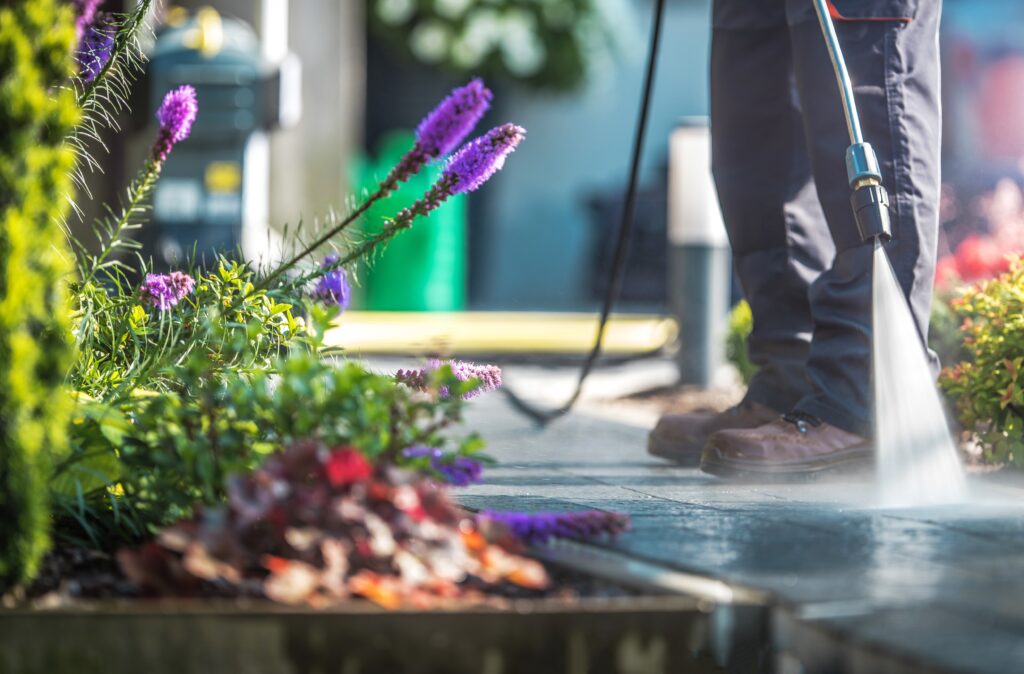 Backyard Garden Cleaning Time with Pressure Washer. Men Cleaning Garden Cobble Stone Path.